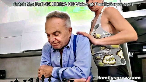 Young blonde babe in tank top teases old man playing chess in kitchen taboo scene
