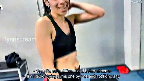 Fit Asian babe in tight black sports bra posing sideways smiling in gym