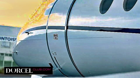 Silver private jet fuselage reflecting golden sunset at airport with round windows