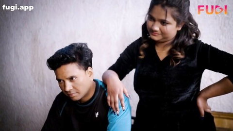 Curvy Indian woman in black velvet top touches man's shoulder teasingly