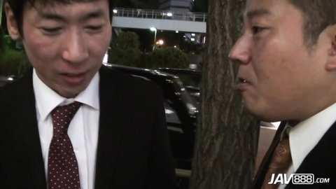 Two suited Asian men talking intimately outdoors at night in JAV