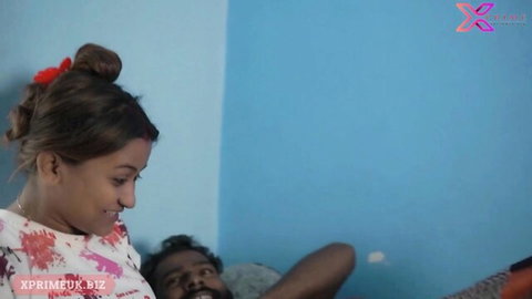 Indian step sister in floral dress smiles teasingly over man on bed morning scene