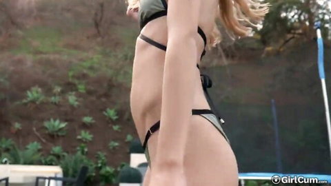 Petite blonde teen in green bikini posing outdoors