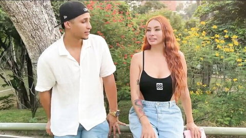 Curvy redhead Latina in black tank top and jeans poses with stranger outdoors