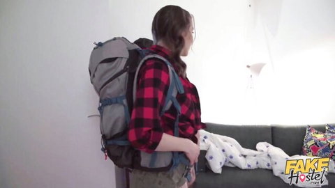 Blonde teen in plaid shirt and shorts with backpack in hostel room