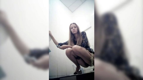 Blonde bombshell in floral dress squats in bathroom, long hair flowing