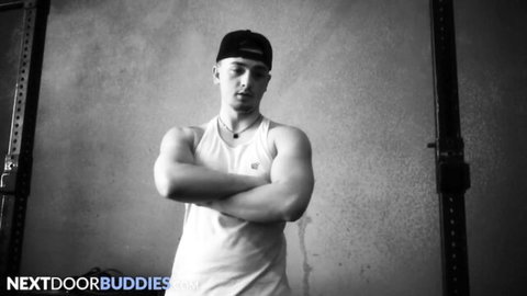 Muscular hung jock in tank top, arms crossed in gym for deepthroat hookup