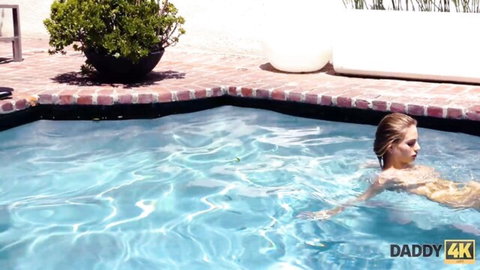 Skinny blonde babe floating nude in backyard pool exposing perky tits and wet body