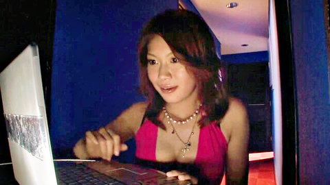 Seductive Japanese babe in pink dress at laptop, big tits hinted