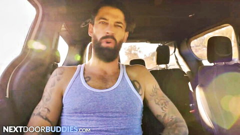 Tattooed bearded hunk Alpha Wolfe in tank top, muscular gay model