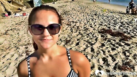 Tan-skinned teen in striped bikini smiling on sunny beach