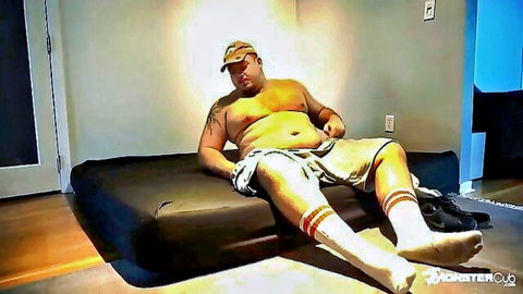 Tattooed chubby amateur man lounging in shorts on bed, solo tease