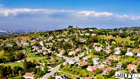Aerial view of sunny suburban hillside neighborhood with upscale homes