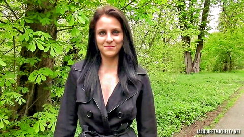Smiling French brunette in open black trench coat showing cleavage outdoors