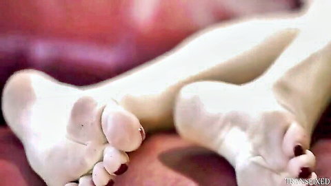 Close-up of pale sexy soles with red toenails spread wide for foot fetish tease