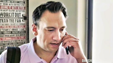 Man in pink shirt talking on phone in gym with motivational posters