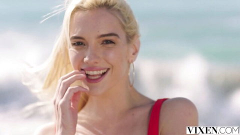 Blonde Kenna James smiling seductively on sunny beach in red top