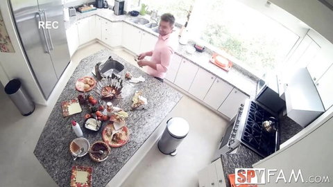 Spy cam captures man in pink shirt cleaning pizza mess on kitchen island