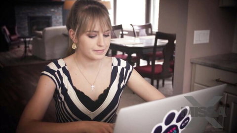 Ivy Wolfe in striped top smiling at laptop in home setting