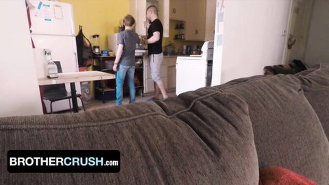 Gay stepbrothers teasing in kitchen with hands gripping hips from behind