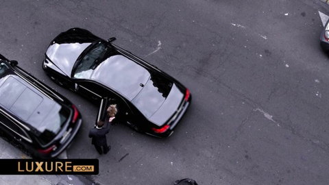 Shiny black luxury sedans parked outdoors with suited man opening car door