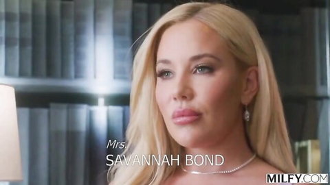 Savannah Bond blonde MILF in white dress, sultry gaze in library