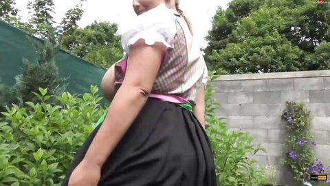 Busty blonde in dirndl dress walking outdoors, massive tits highlighted