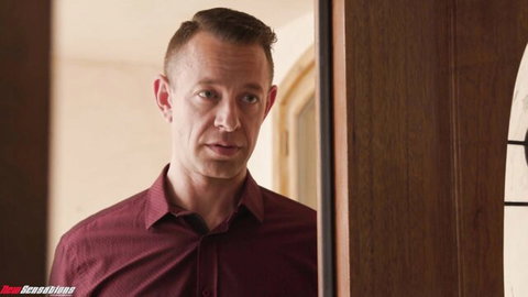 Handsome short-haired man in maroon shirt standing in wooden doorway