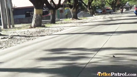 Sunny Filipino street with tricycles, motorbikes, tropical trees and buildings
