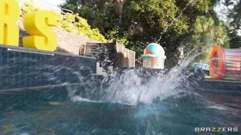 Brazzers pool splash with yellow letters, colorful inflatables, palm trees and wild water action