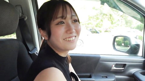Cute Asian babe with bangs smiling happily in car passenger seat wearing black top