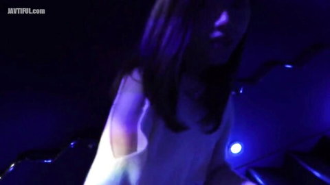Seductive Asian babe in ripped white top exposing shoulder under blue club lights