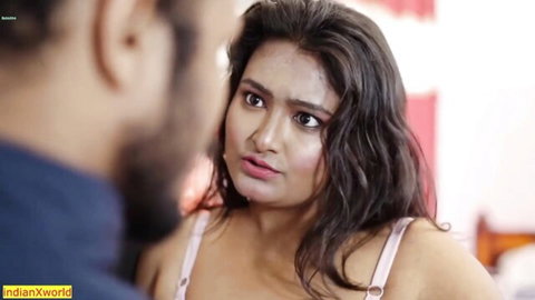 Busty Indian wife in low-cut pink top stares surprised at bearded husband in bedroom