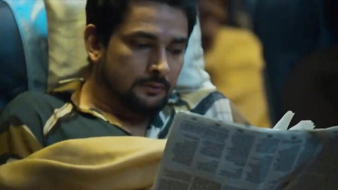 Buddy Hollywood reading newspaper in Indian bus scene with Lollypop Gcup