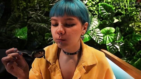 Turquoise haired pierced teen with freckles holds spoon to pouty lips teasingly