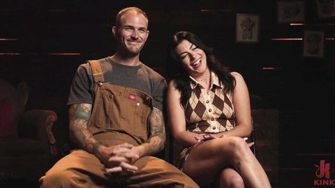 Gal Ritchie smiling intimately with tattooed hunk in overalls and checkered dress