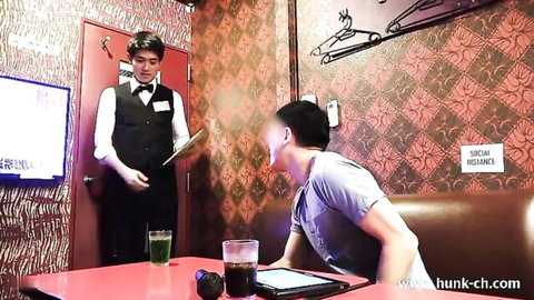 Asian waiter in uniform serving handsome customer in lounge bar