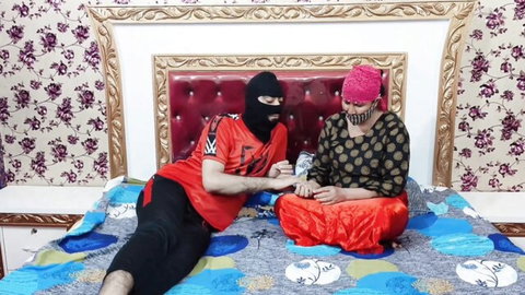 Masked Indian man in FUCK shirt holds hands with mature South Asian woman in salwar on ornate bed