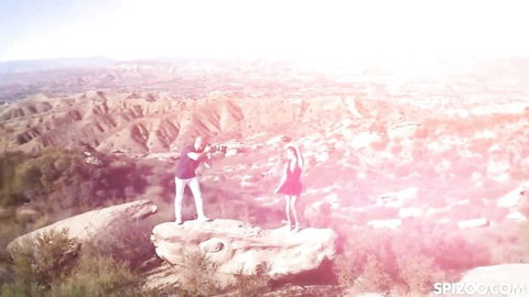 Vina Sky in red dress on cliff with partner in scenic canyon overlook