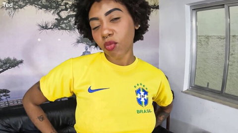 Sexy curly-haired Brazilian babe in yellow soccer jersey sticks out tongue teasingly