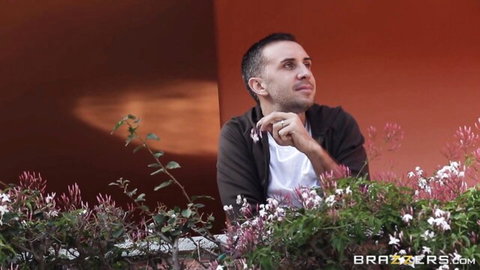 Stevie Shae in pensive pose on balcony with orange wall and flowers, Brazzers