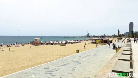 Sunny Barcelona beach promenade with golden sand, umbrellas, distant people and ocean view