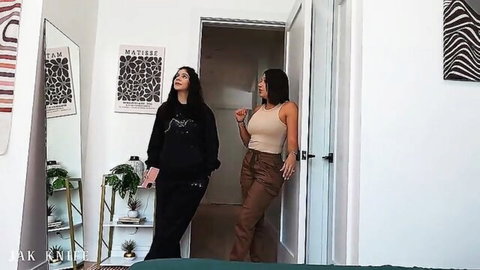 Two sexy brunette babes standing in modern bedroom wearing tight clothes