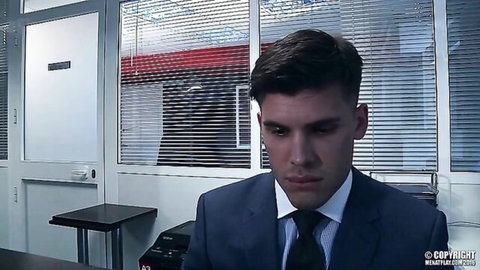 Handsome muscular young man in tight suit looking intense through office blinds