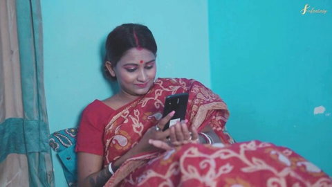Curvy Desi wife in red saree smiles while checking phone, teasing massive natural boobs