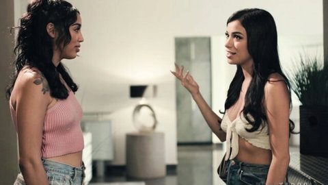 Two Latinas in tank tops and jeans chatting intimately