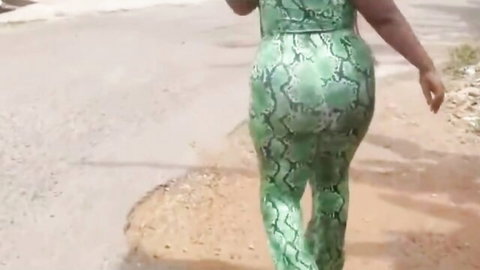 Ebony babe with huge ass in tight green snake print pants walking away teasing on dirt road