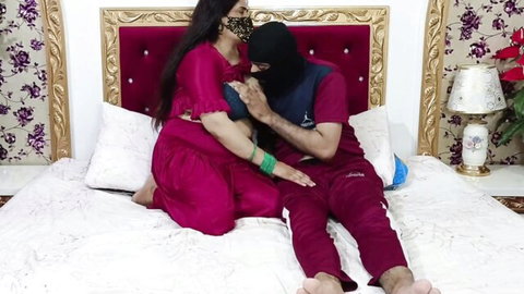 Curvy Indian housewife in red dress grabs masked man's cock bulge on ornate bed