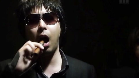 Stylish man in sunglasses sucking on thick cigar in dark suit closeup