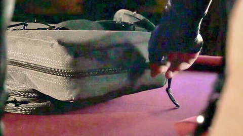 Gloved hand gripping gray duffel bag on purple pool table in dim light
